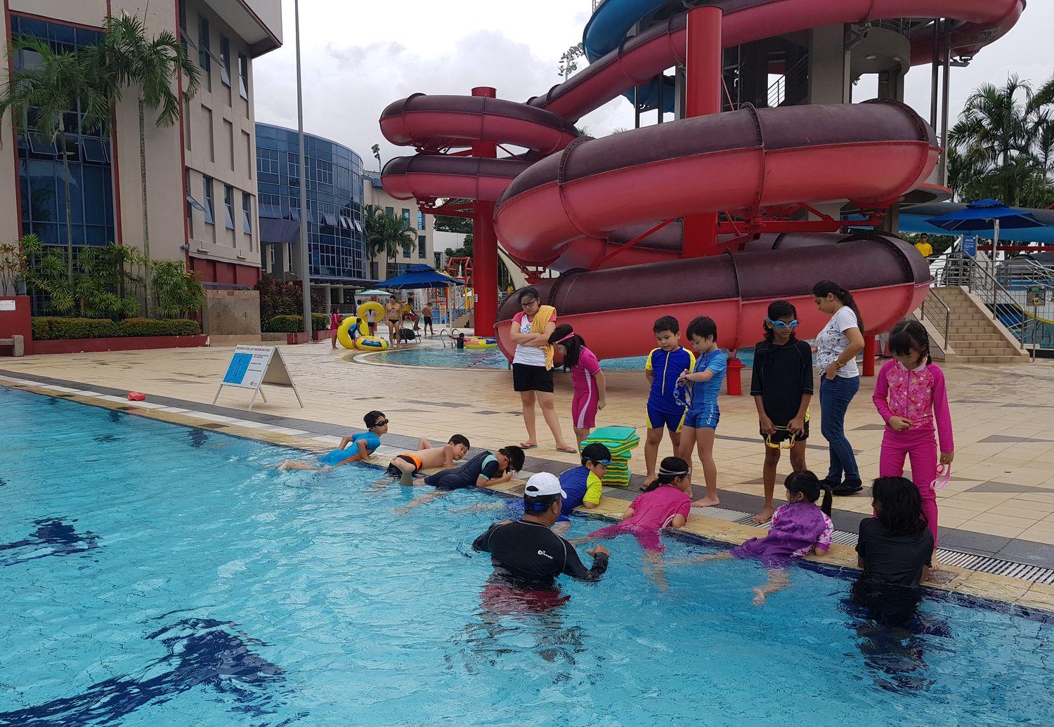 Swimmers gathered along the pool edge with their coach