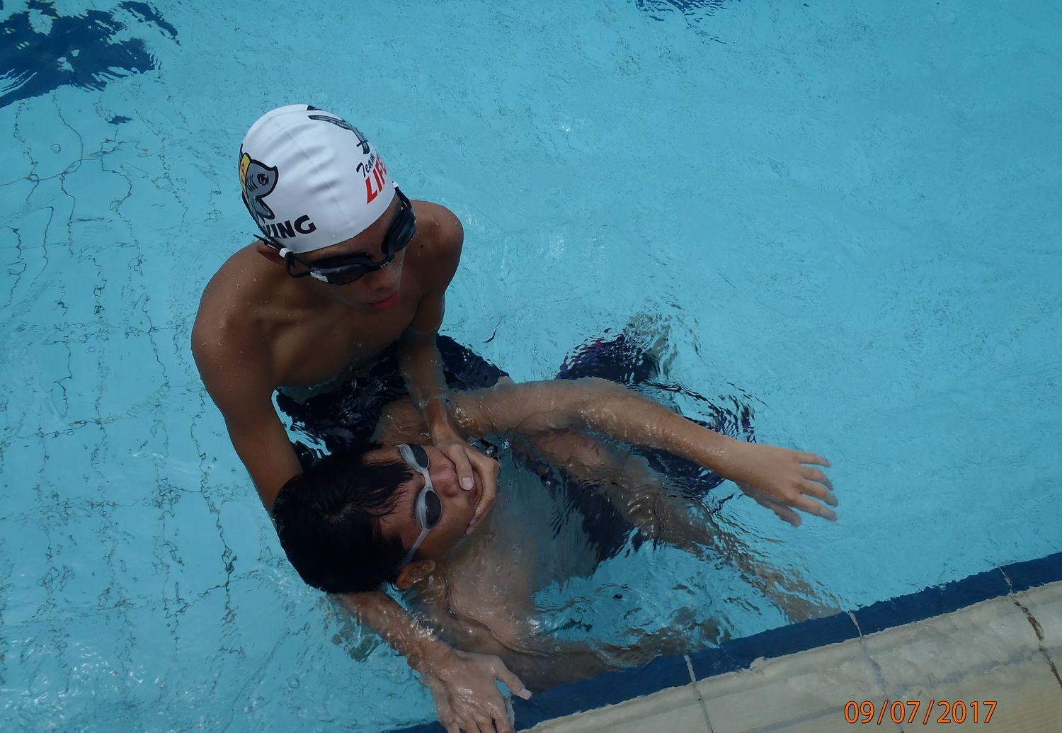 A coach guiding a swimmer through a drill